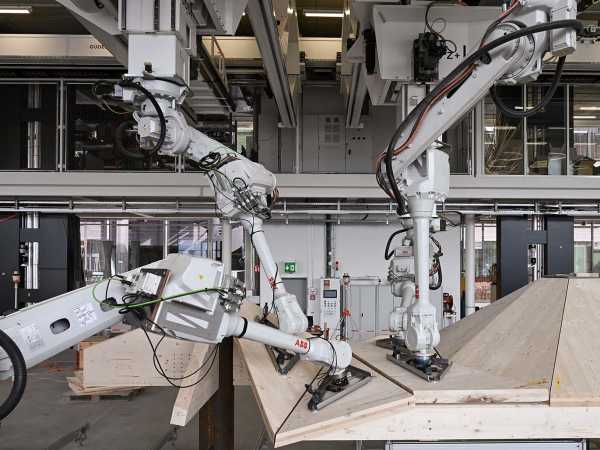 Roboterarme halten Holzplatten in einer Fertigungshalle