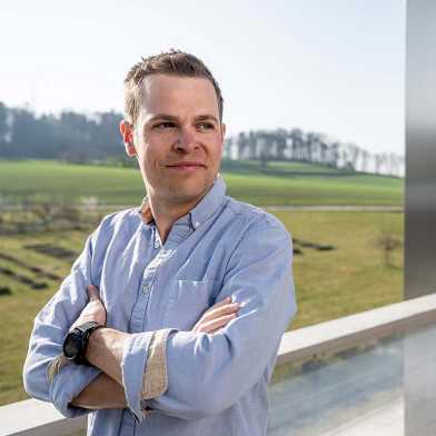 Martin Hofmann steht mit verschränkten Armen auf einem Balkon des ETH-Campus Hönggerberg