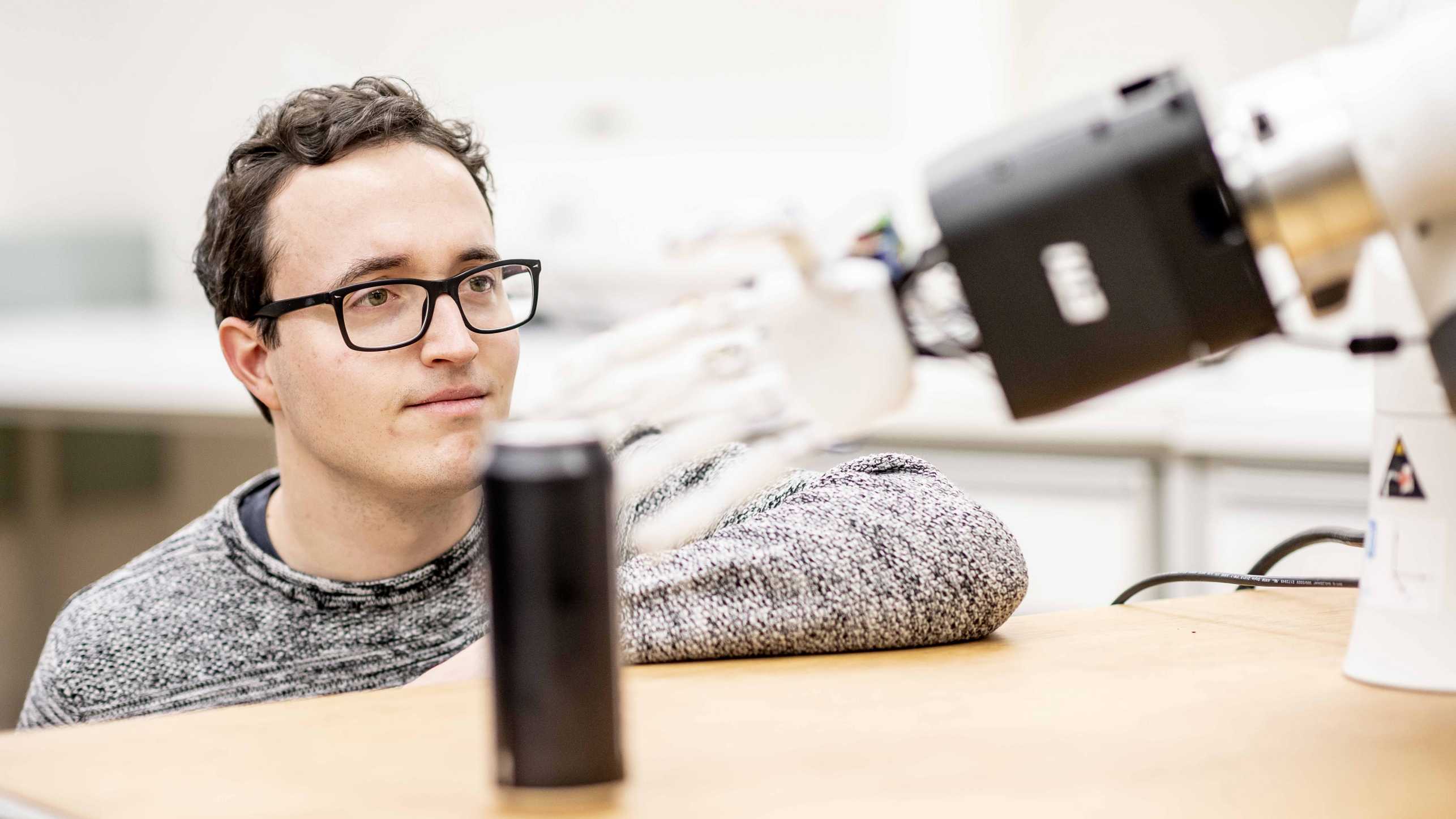 Elvis Nava schaut der weissen Roboterhand dabei zu, wie sie nach einer Dose greift. 