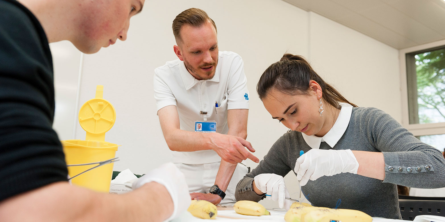 Studierende lernen im Bachelor in Humanmedizin praktisch anhand von Bananen, wie sie Wunden vernähen.