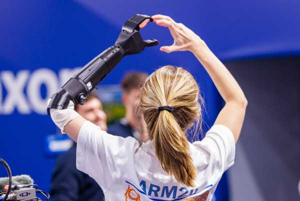 Eine Frau mit einer Armprothese bldet mit den Händen eine Herz in die Luft.