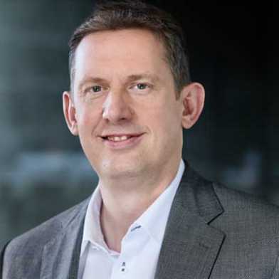 Ein Porträtbild zeigt den ETH-Vizepräsidenten Christian Wolfrum vor dunklem Hintergrund.