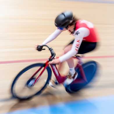 A woman on a racing bike on an indoor race track.