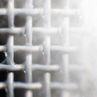 Metal grid on which water drops are visible