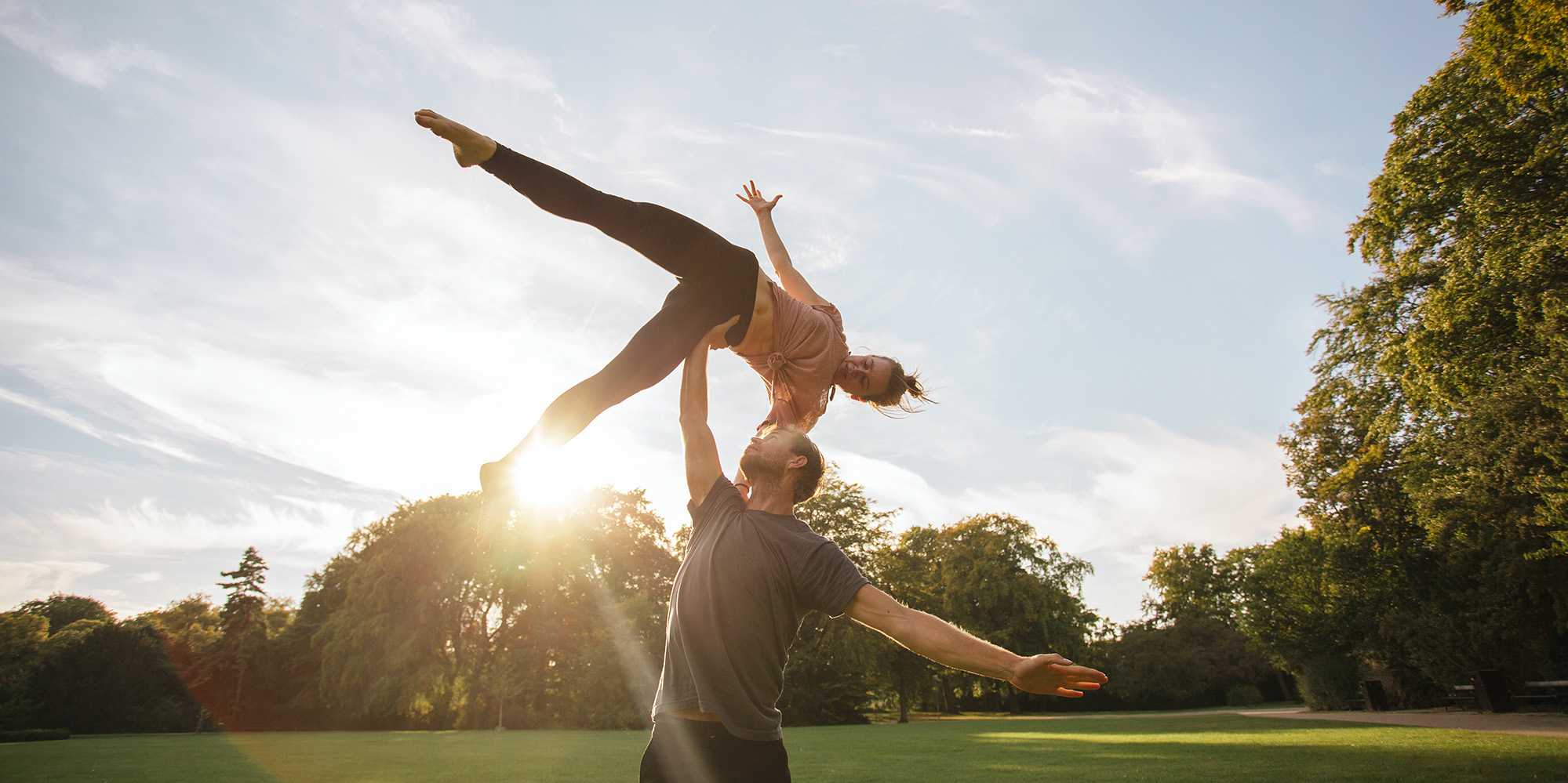 two people doing a lifting acrobatic figure in a meadow