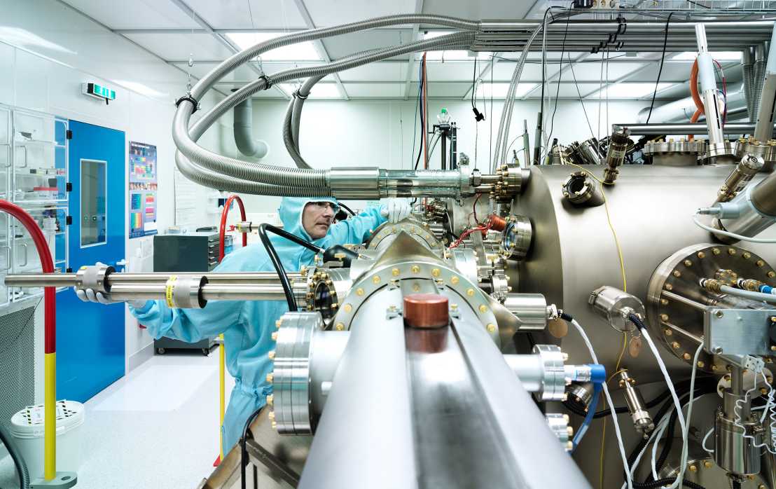 A man in a protective suit cleans a laboratory room.
